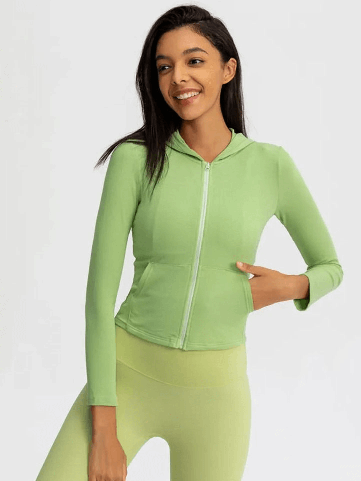 Woman wearing a green sports jacket with hood and long sleeves, perfect for active outdoor activities.